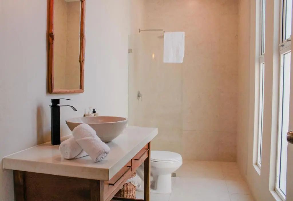 Helles Badezimmer mit beigem Waschtisch, Toilette und begehbarer Dusche.
