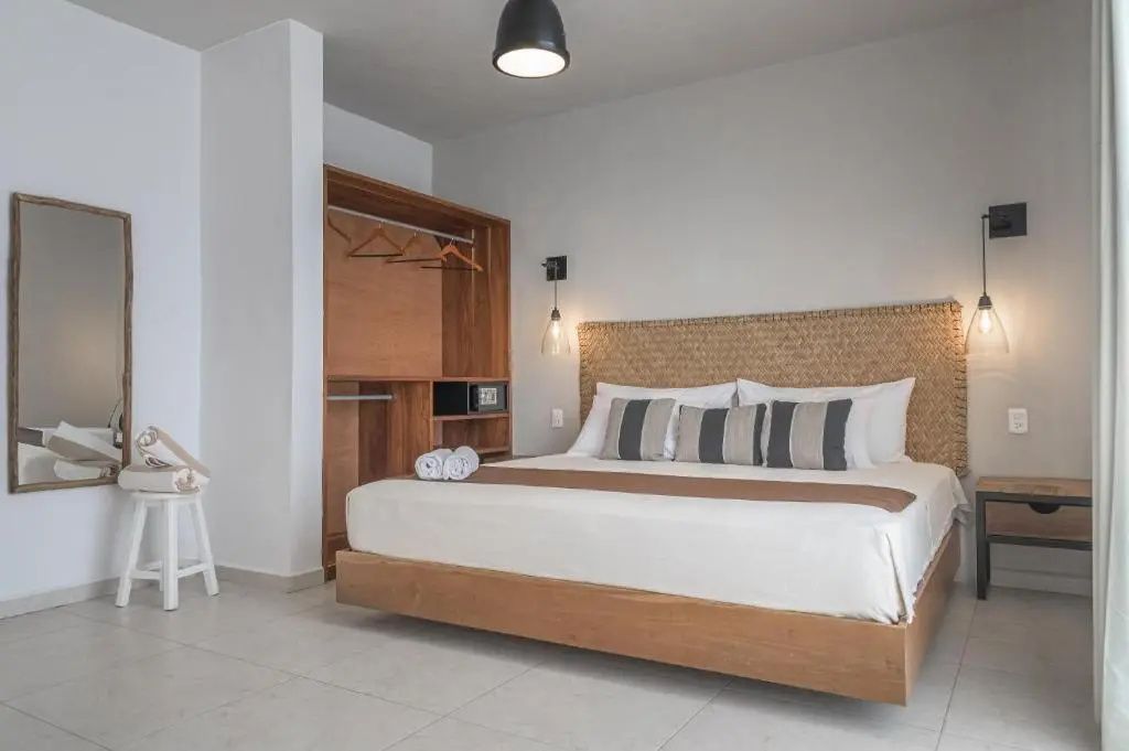 Hotelzimmer mit großem Doppelbett, geflochtenem Kopfteil und offenem Kleiderschrank.
