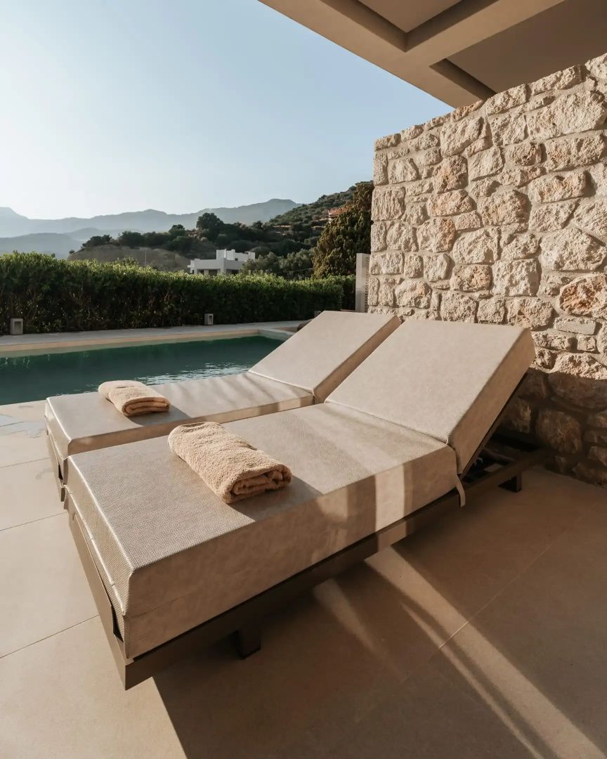 Zwei Sonnenliegen auf einer Terrasse am Pool mit Blick auf Berge.