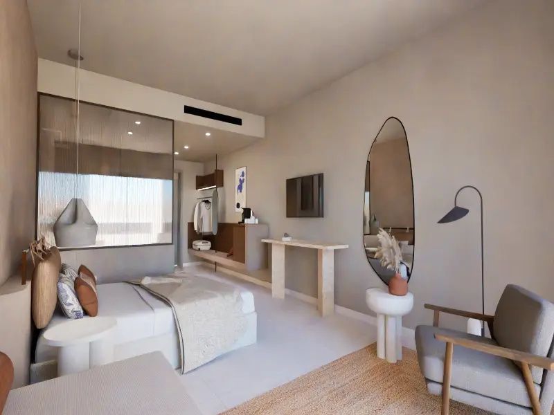 Helles Hotelzimmer mit Doppelbett, Sessel, Flachbildfernseher und Wandspiegel.
