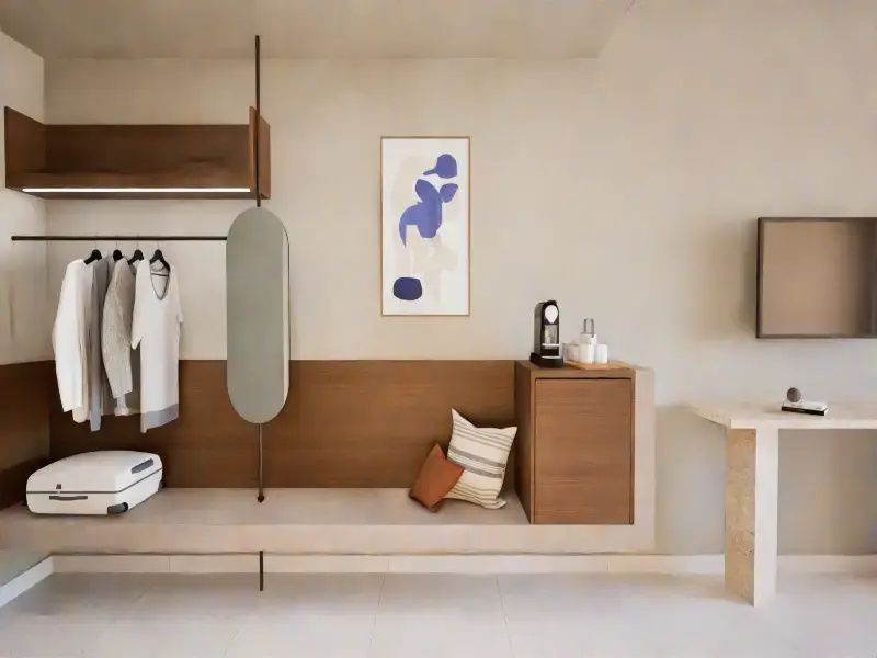 Offene Garderobe mit Sitzbank, Kaffeemaschine und Kunstwerk an der Wand.
