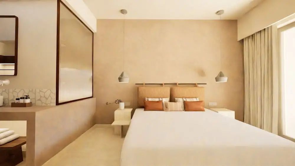 Helles Hotelzimmer mit Doppelbett, Nachttischen und zwei modernen Pendelleuchten.