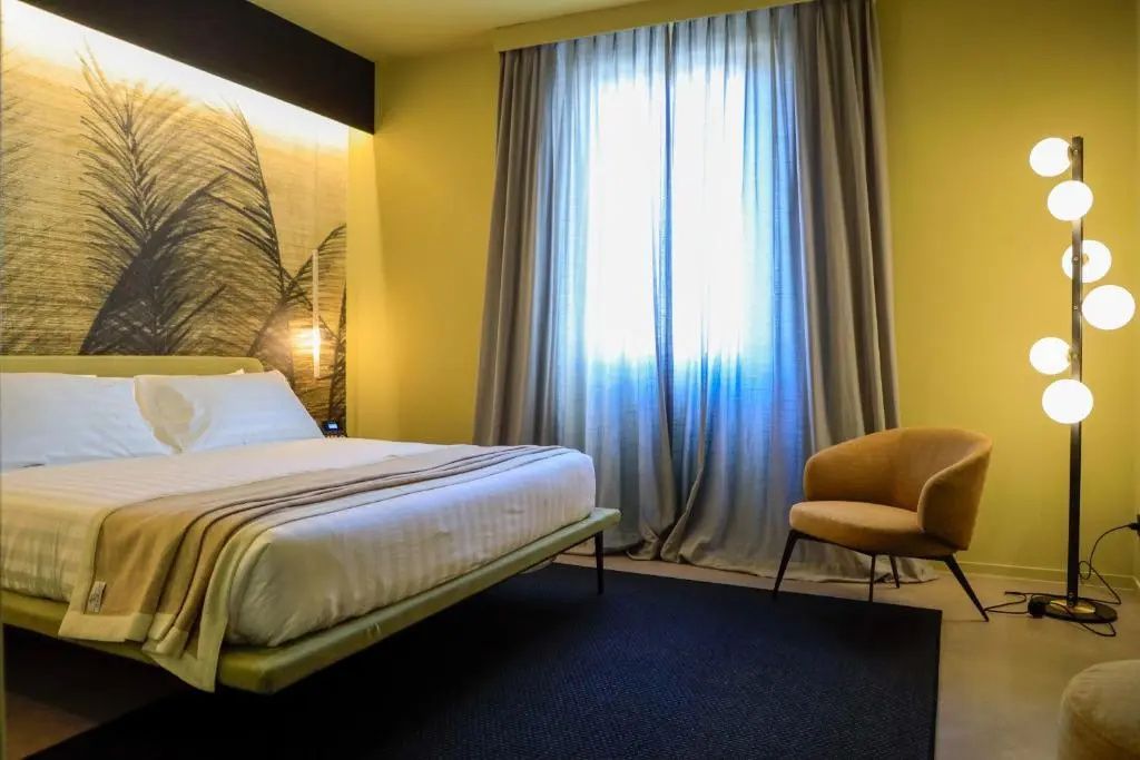 Schlafzimmer mit Doppelbett, gelbem Sessel und einer Wand mit Palmendesign.