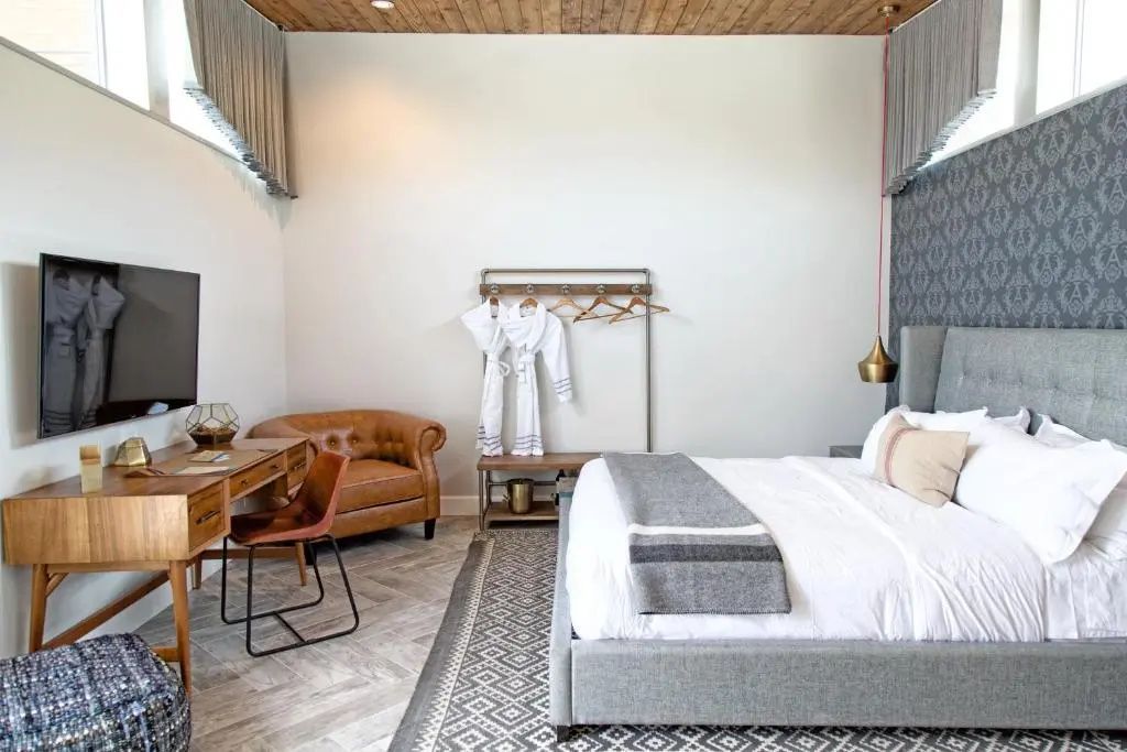 Hotelzimmer mit Schreibtisch, braunem Ledersessel und Ständer für Bademäntel.