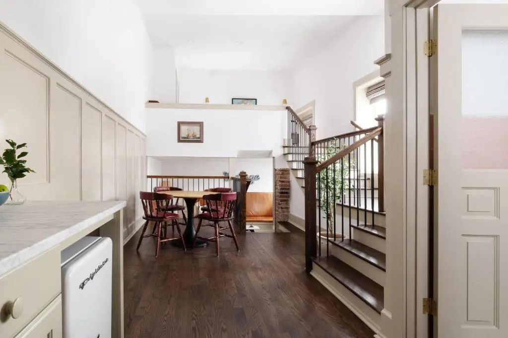 Offener Wohnbereich mit Holzfußboden, Treppe zum Zwischengeschoss und Esstisch.