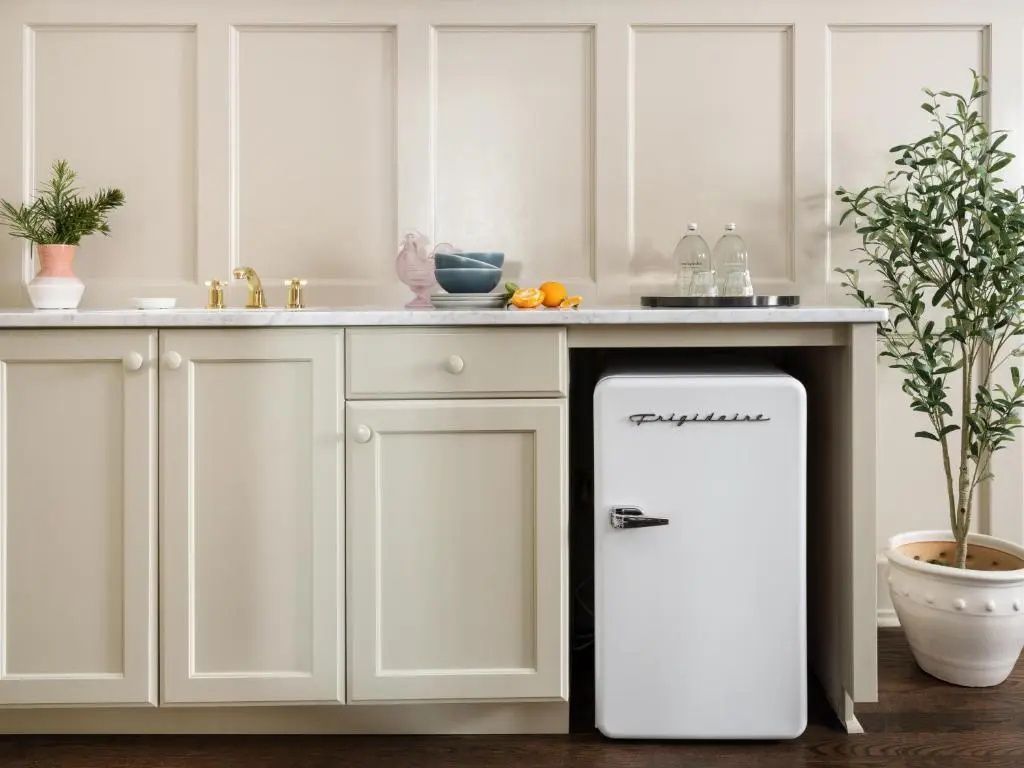 Weißer Mini-Kühlschrank im Retro-Design unter einer hellen Marmor-Arbeitsplatte.
