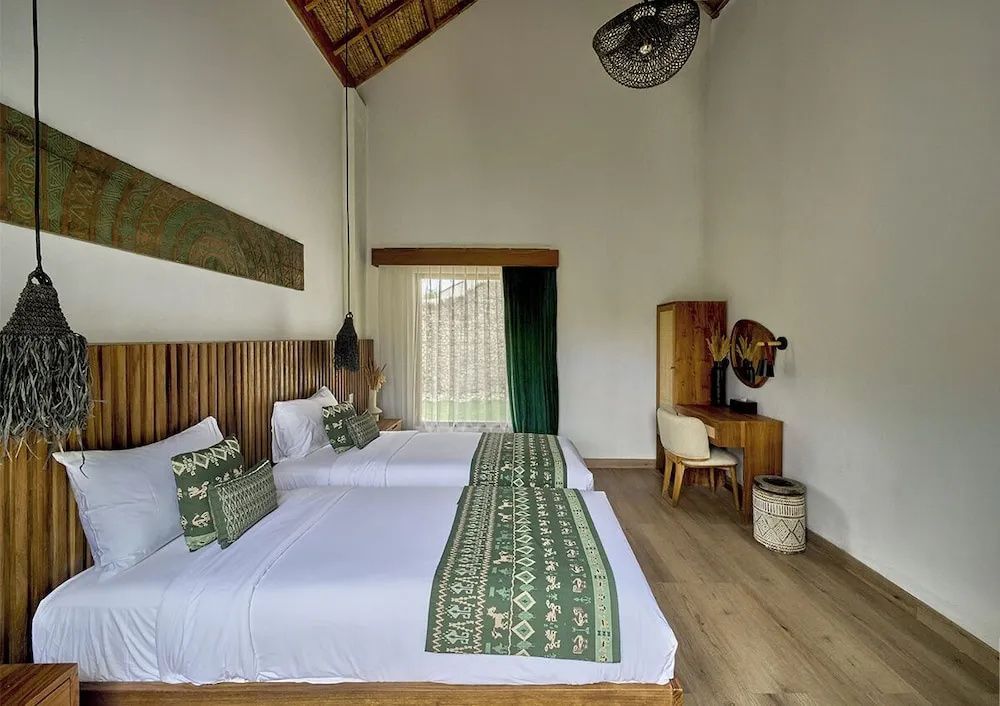 Helles Schlafzimmer mit zwei Einzelbetten, Holzvertäfelung an der Wand und einem Schreibtisch.