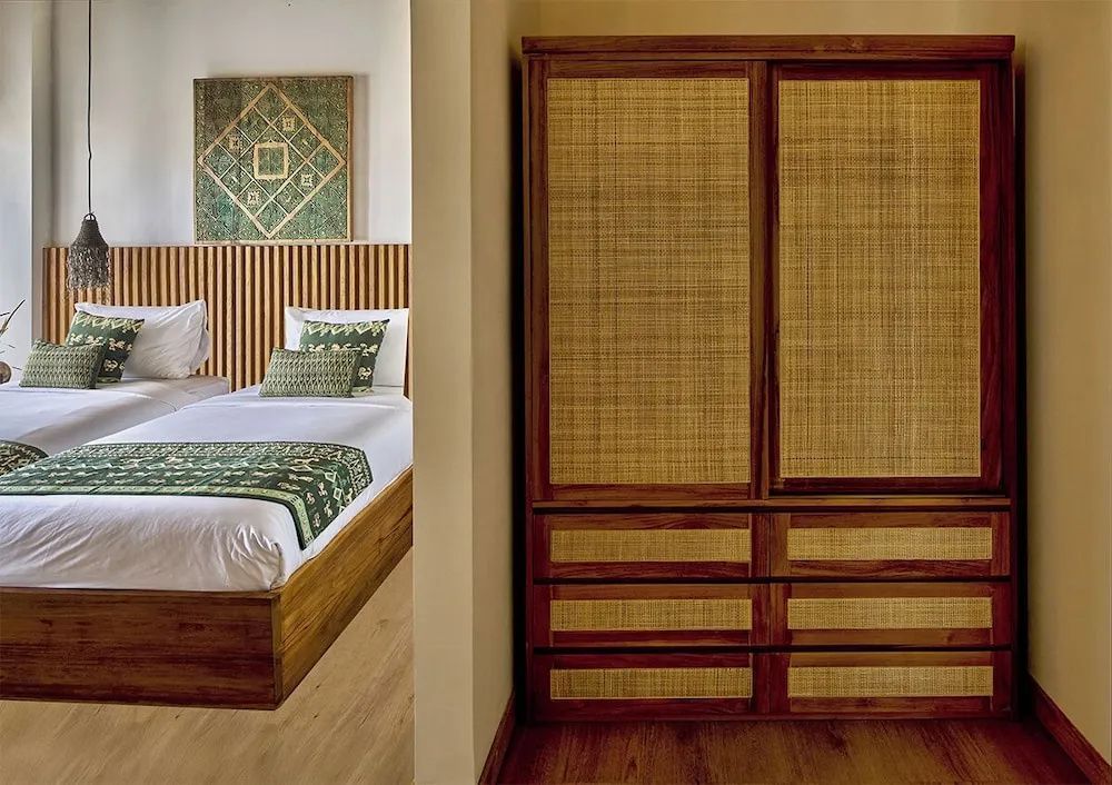 Großer Holzschrank mit Rattanfronten neben einem Bett mit grüner Dekoration.