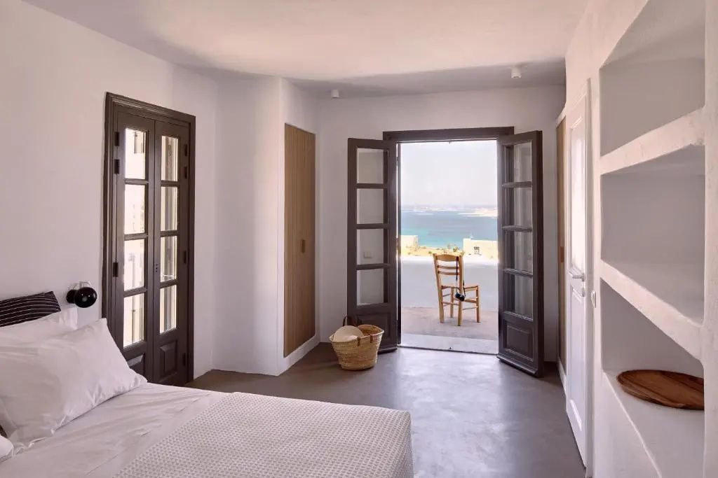 Zimmer mit geöffneter Terrassentür und Blick auf das blaue Meer.