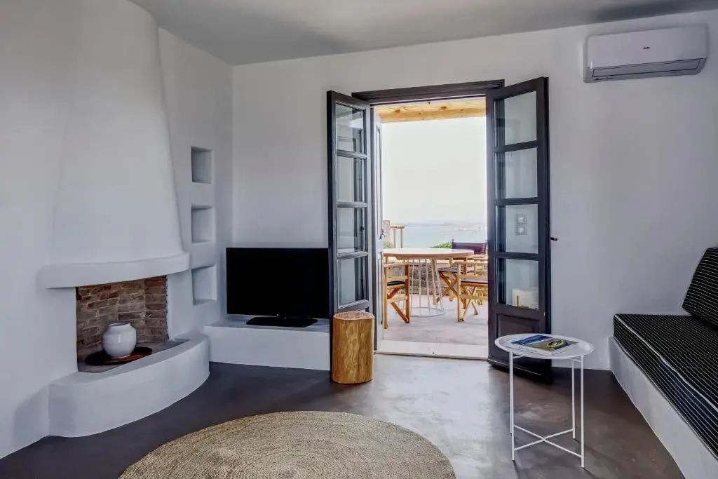 Wohnzimmer mit Kamin und geöffneter Terrassentür mit Blick auf das Meer und die Terrasse.