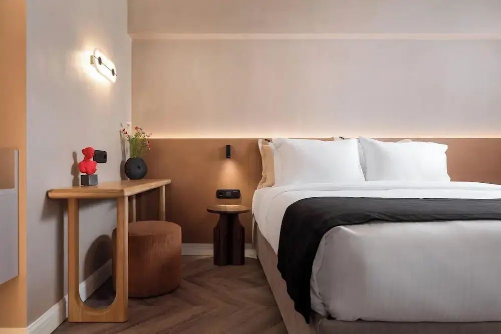 Schlafbereich der Suite mit Doppelbett, Nachttisch und Holzschreibtisch.