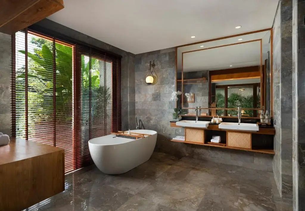 Badezimmer mit frei stehender Badewanne, Doppelwaschtisch und großem Spiegel.