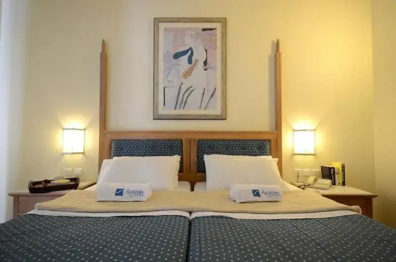 Doppelbett mit blauem Kopfteil, Holzrahmen, Nachttischlampen und Bild an der Wand.