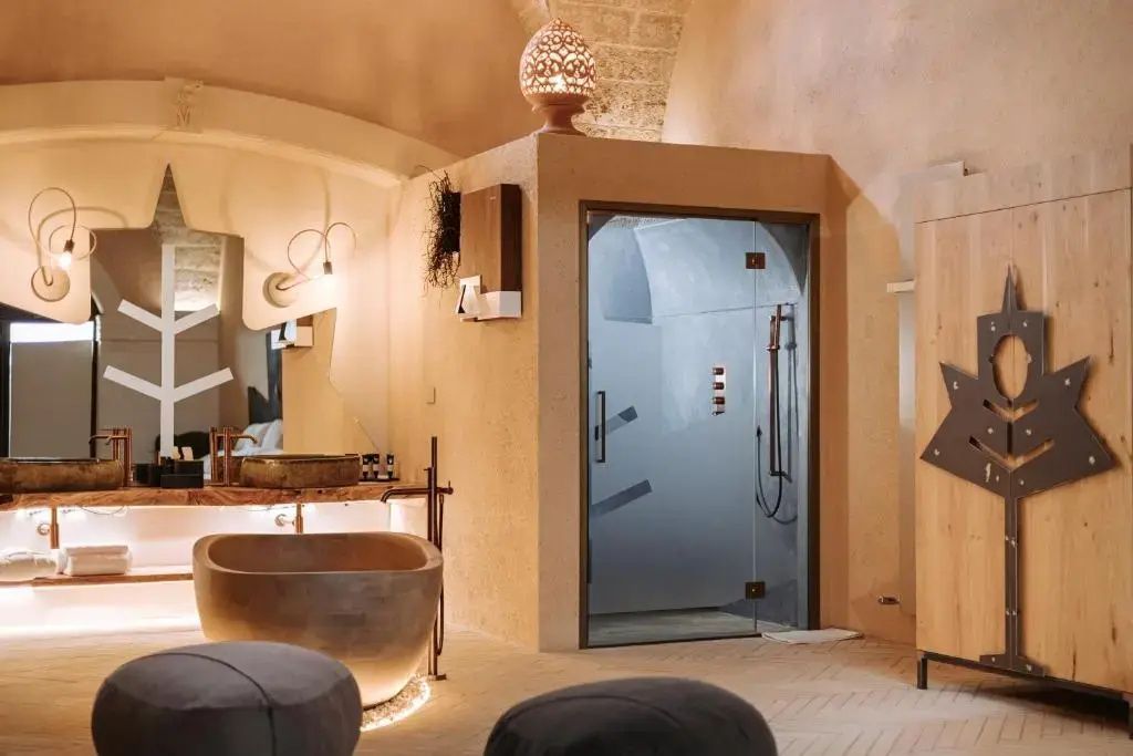 Badebereich im Zimmer mit moderner Dusche aus Glas freistehender Wanne und Steinwaschtisch.