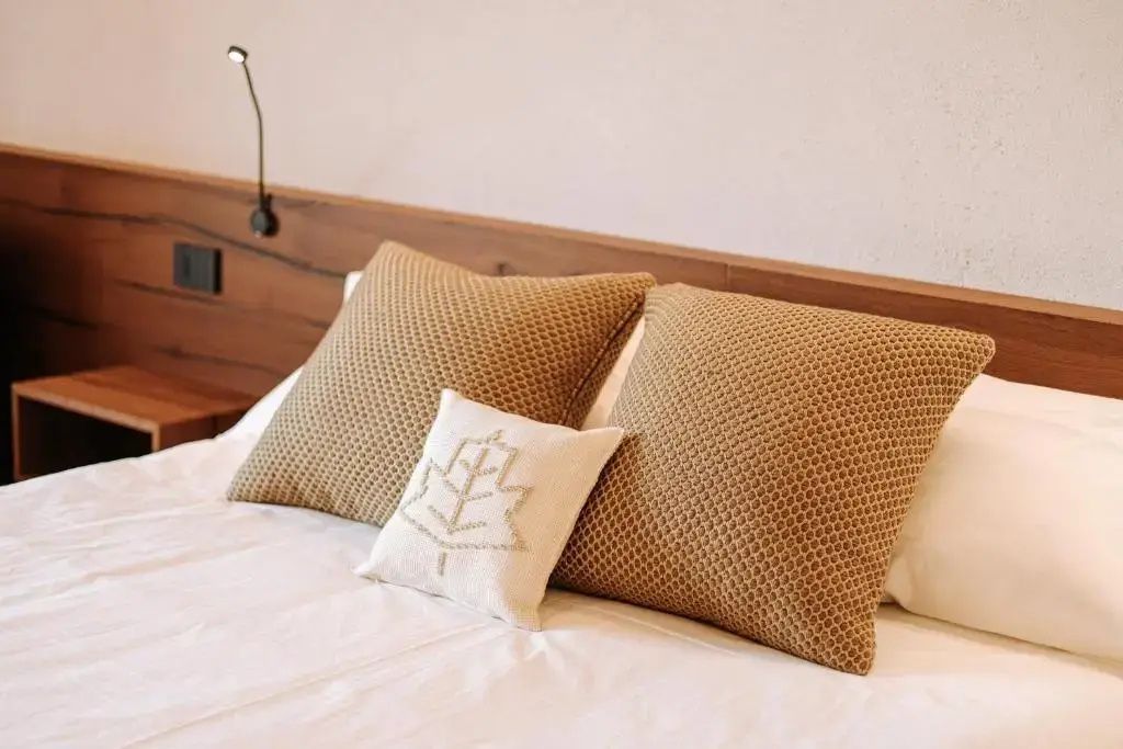 Nahaufnahme von braunen Kissen und einem gestickten Dekokissen auf dem Bett.