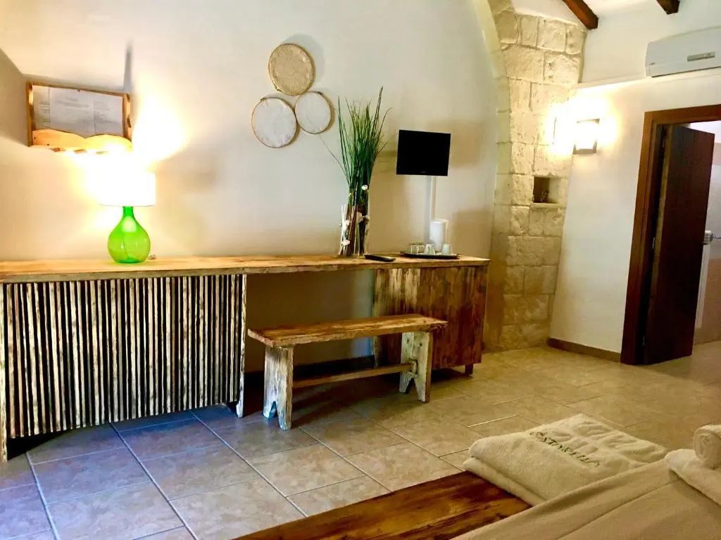 Holzsideboard mit Holzsitzbank, Wandlampe und Fernseher im Zimmer.