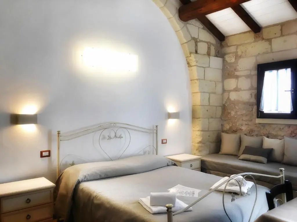 Schlafzimmer mit Eisenbett, gewölbter Steinwand und Holzgebälk an der Decke.