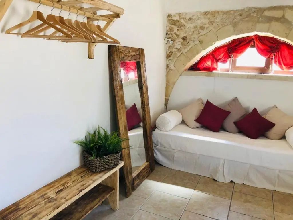 Ecke des Zimmers mit Holzgarderobe, großem Holzspiegel und kleiner Bank mit Pflanze.