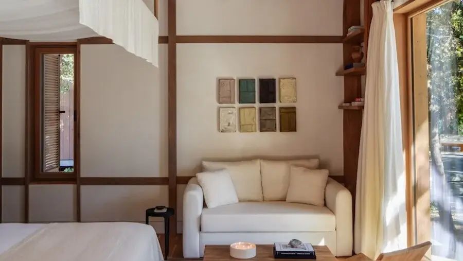Sitzbereich im Zimmer mit weißem Sofa, Holztisch und Dekoration an der Wand.