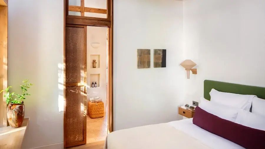 Helles Hotelzimmer mit Doppelbett, Holzschiebetür und kleinen Wandnischen.