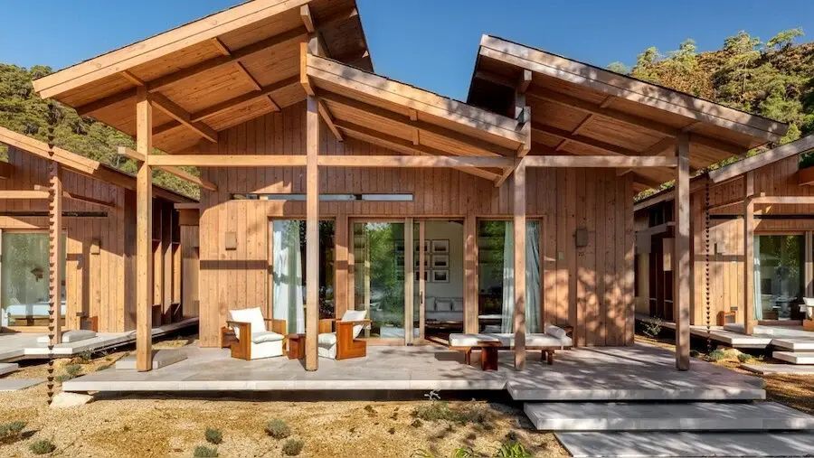 Holzgebäude mit großer Terrasse, Sitzgelegenheiten und gläsernen Schiebetüren.