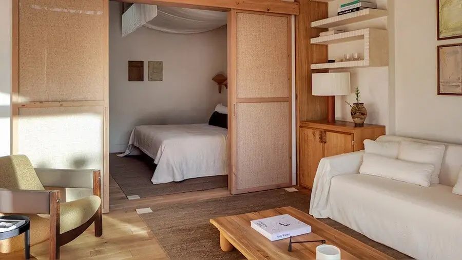Schlafbereich mit Doppelbett, getrennt durch eine Schiebetür aus Holz.
