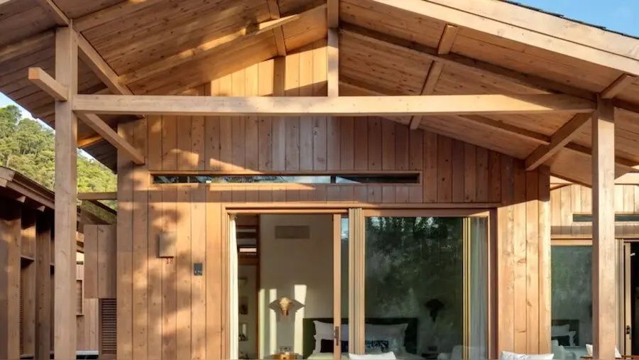 Holzfassade einer Unterkunft mit Schiebetür aus Glas und Blick in den Schlafbereich.