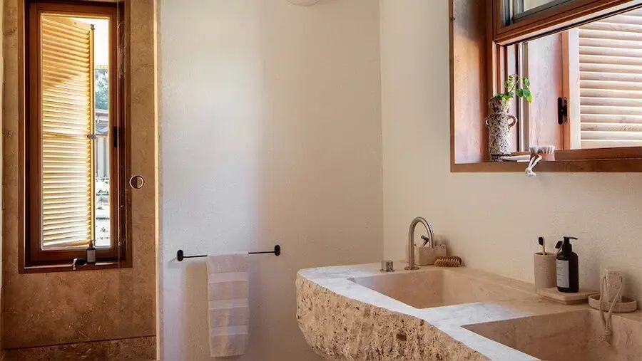 Badezimmer mit einem massiven Waschbecken aus Naturstein und einem Handtuchhalter an der Wand.