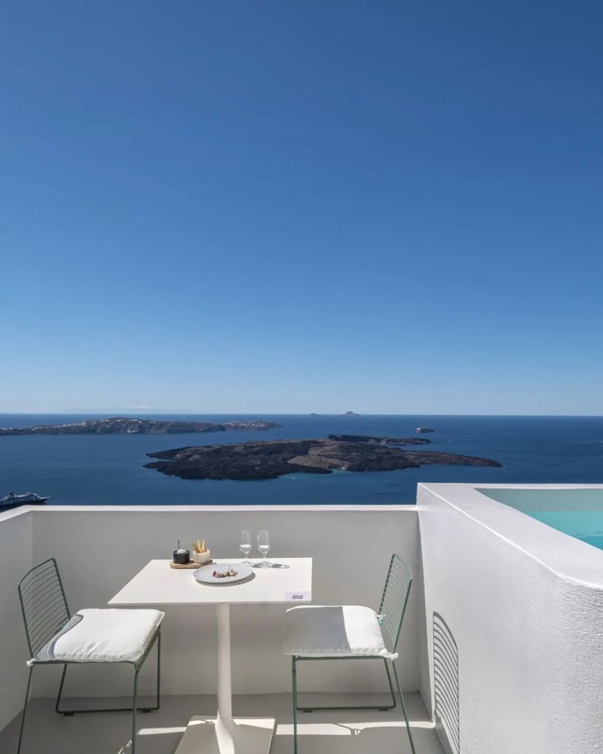 Weißer Balkon mit Tisch und Stühlen und Blick auf das Meer und Vulkaninseln.
