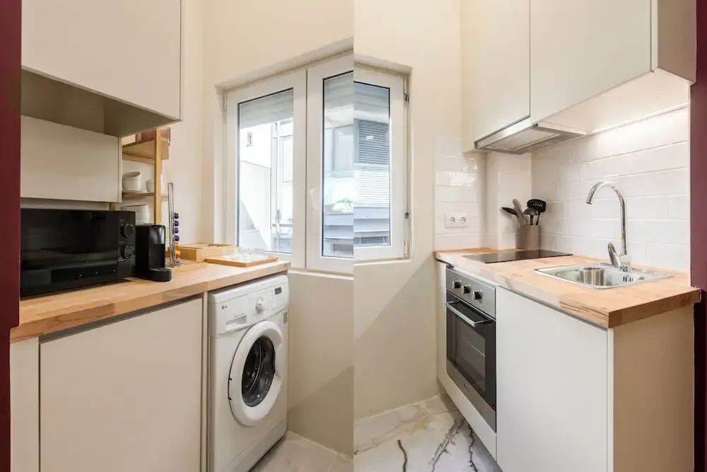 Einbauküche mit Waschmaschine, Kochfeld, Backofen und kleinem Fenster.
