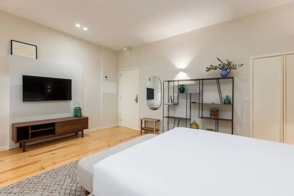 Modernes Zimmer mit Fernseher auf Sideboard, Metallregal und ovalem Wandspiegel.