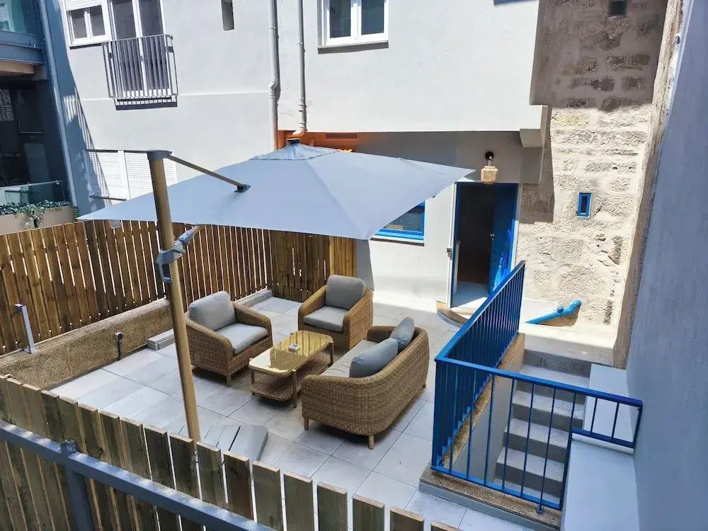 Blick von oben auf eine Terrasse mit Holzzaun, Rattansitzmöbeln und blauem Geländer.
