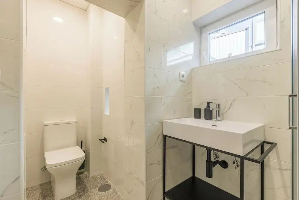 Hell gefliestes Badezimmer mit modernem Waschtisch und Toilette.