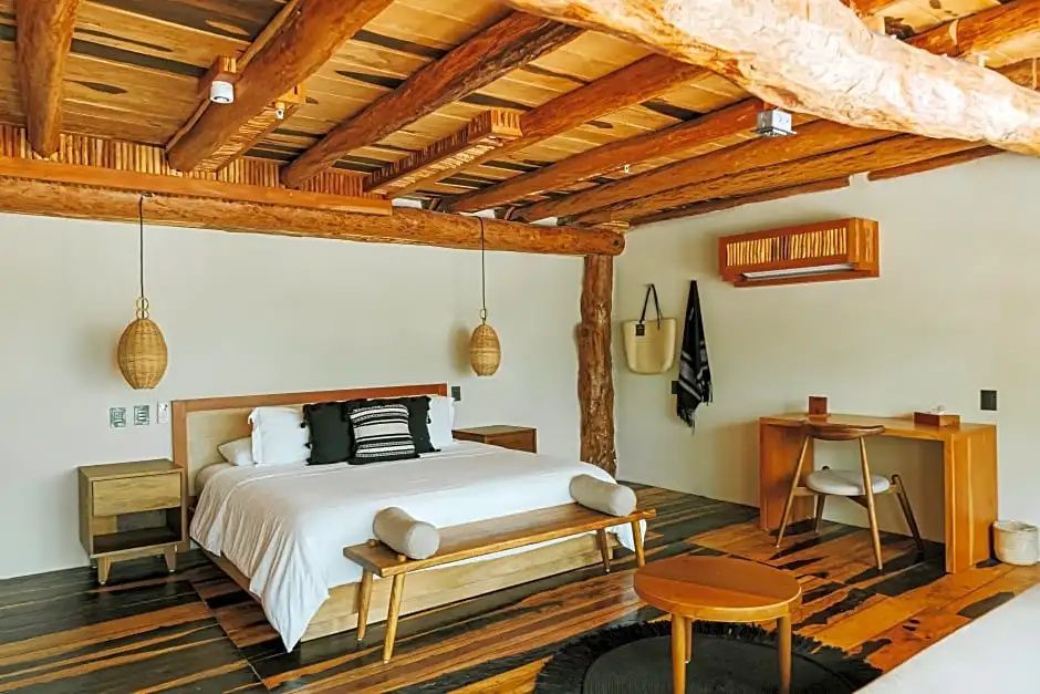 Schlafzimmer mit rustikaler Holzdecke, großem Doppelbett und Schreibtisch aus Holz.