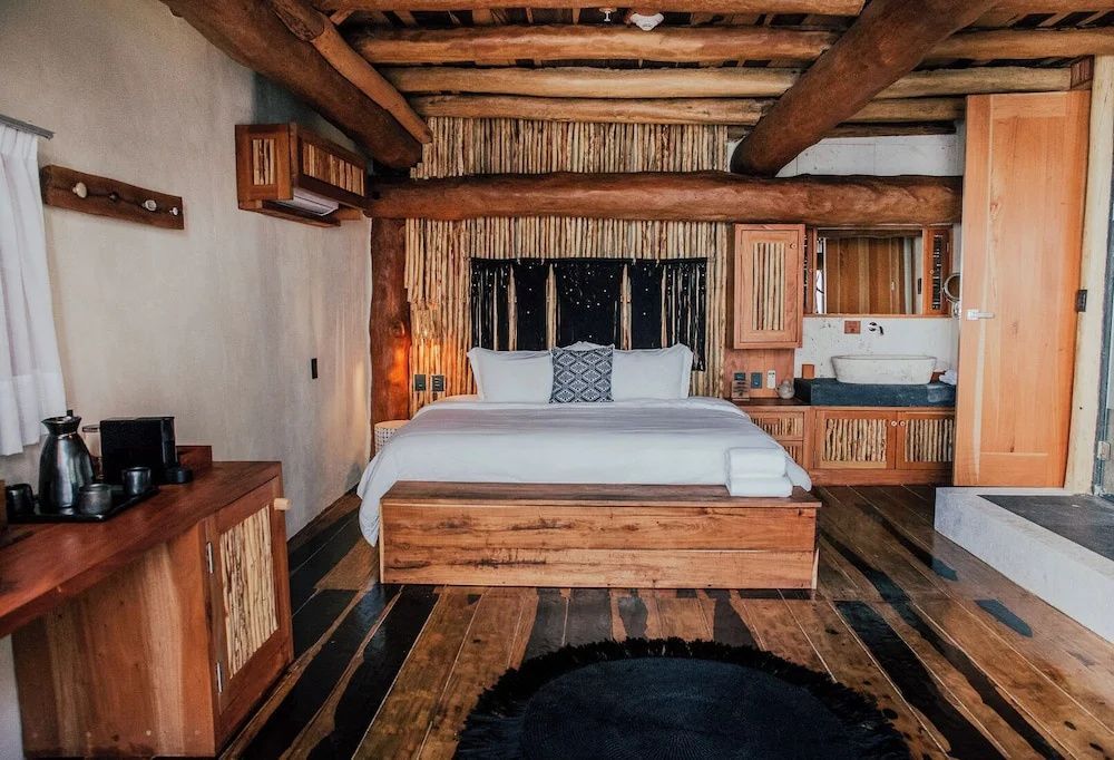 Rustikales Schlafzimmer mit Holzbalkendecke, Doppelbett und Parkettboden