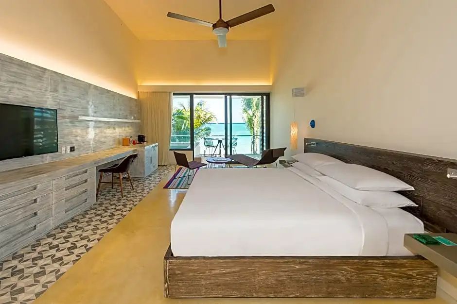 Hotelzimmer mit Doppelbett, Schreibtisch und Balkon mit Blick auf das Meer.