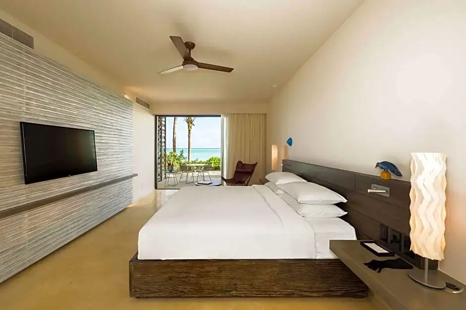 Modernes Hotelzimmer mit Doppelbett, Wand-TV und Balkonzugang mit Meerblick.