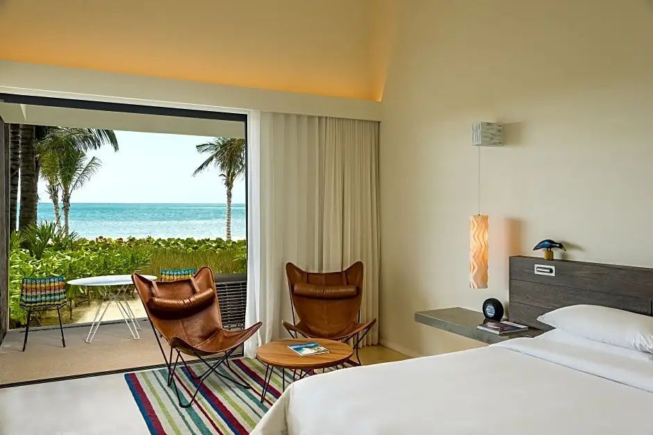 Sitzbereich im Hotelzimmer mit Lederstühlen und Blick auf den Strand und das Meer.