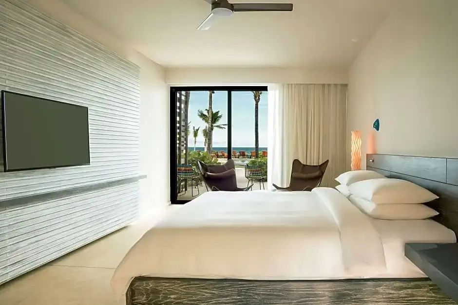Helles Hotelzimmer mit Doppelbett, Flachbild TV und Schiebetür zur Terrasse.