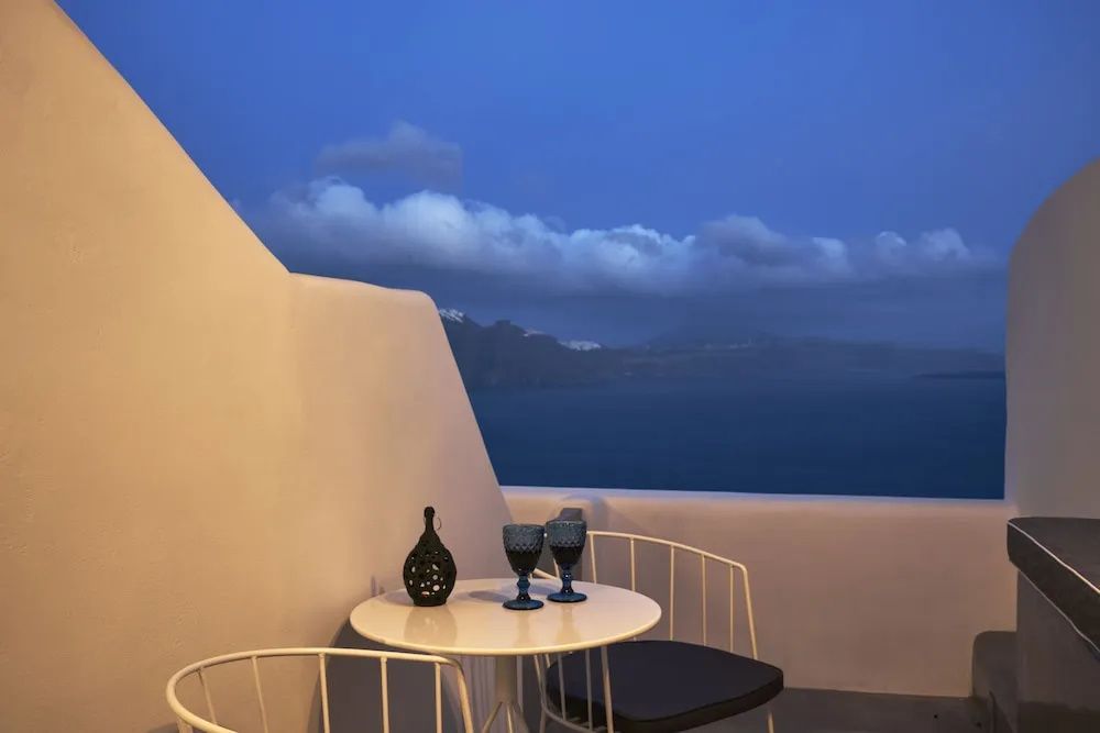 Balkon mit Tisch und Stühlen sowie Blick auf das Meer in der Abenddämmerung.