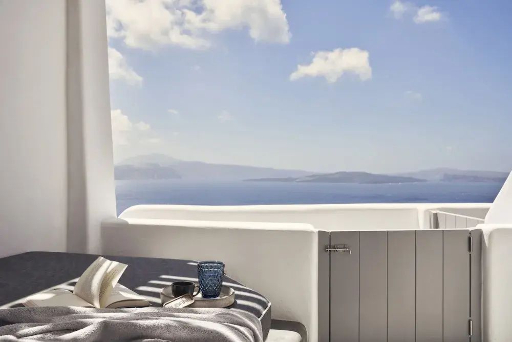 Sitzbereich auf einem Balkon mit einem Buch und Aussicht auf das Meer und Inseln.