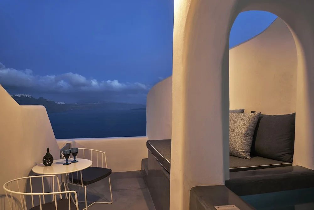 Terrasse mit Sitznische, Tisch und Panoramablick auf das Meer am Abend.