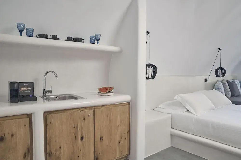 Kleine Küchenzeile mit Spülbecken und Holzschrank neben dem Schlafbereich.