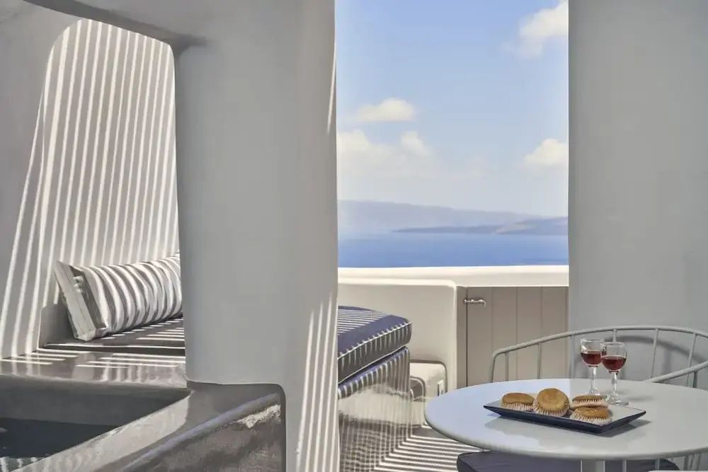 Sitzbereich auf einer weißen Terrasse mit Tisch und Weitblick auf das Meer.