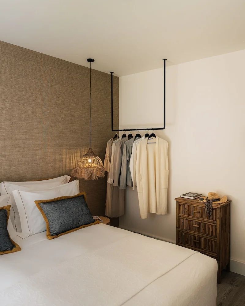 Doppelbett mit Kissen, geflochtene Lampe und eine Kleiderstange im Zimmer