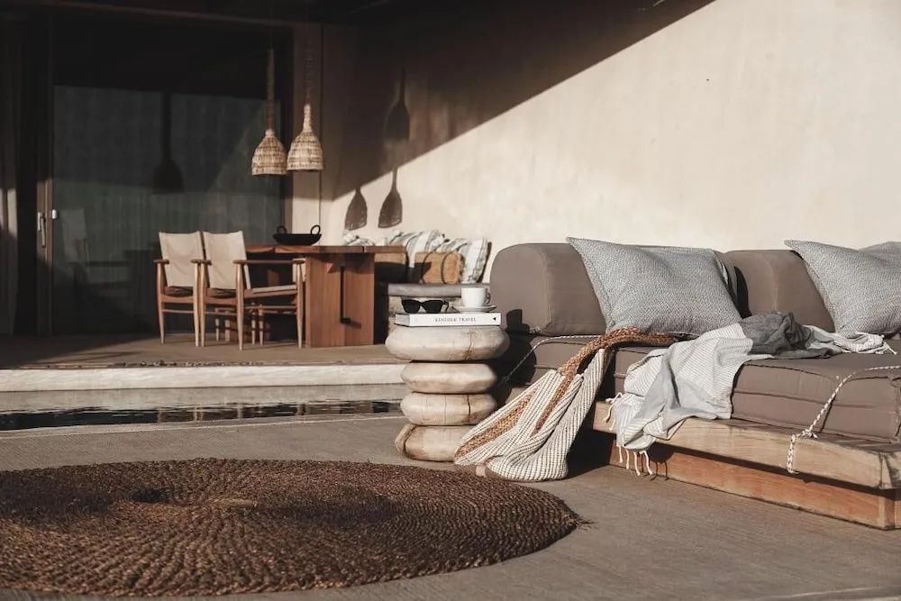 Schattige Terrasse mit einem Sofa, Beistelltisch und geflochtenen Lampen.