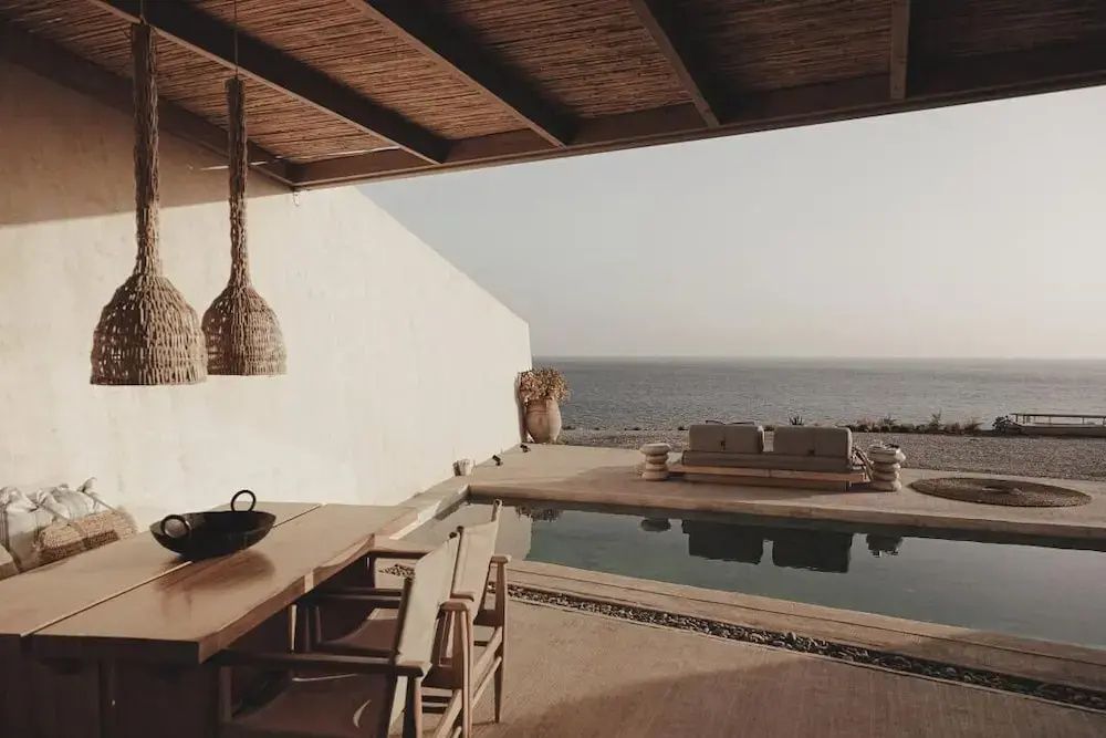Terrassenbereich mit Privatpool, Holz-Esstisch und Blick auf das offene Meer.