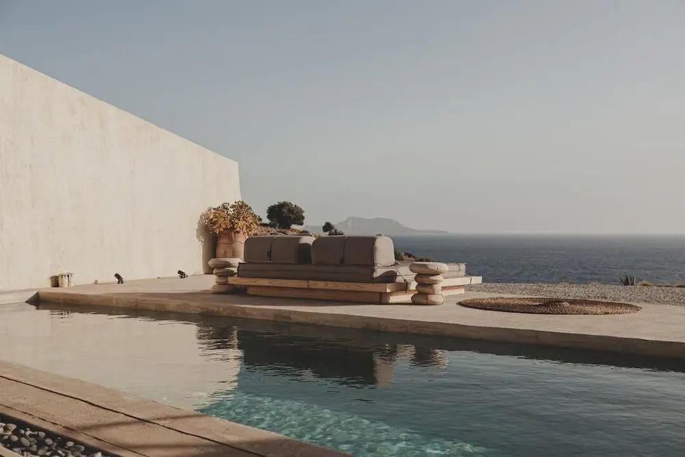 Sitzbank am Rand eines Pools auf einer Terrasse mit Blick auf das offene Meer.