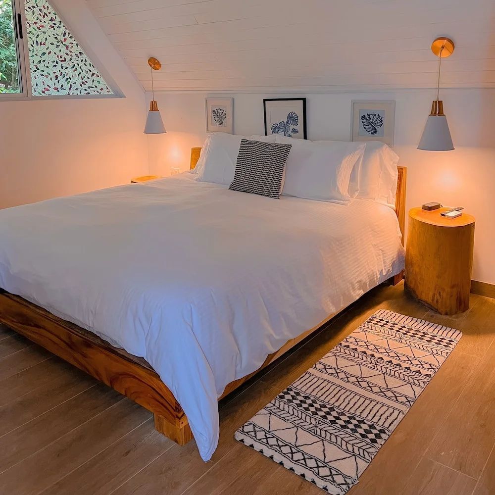 Doppelbett aus Holz unter einer Schräge mit hängenden Nachttischlampen.