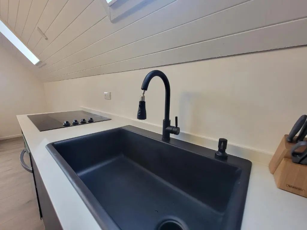 Schwarzes Küchenspülbecken mit moderner Armatur auf einer hellen Arbeitsplatte